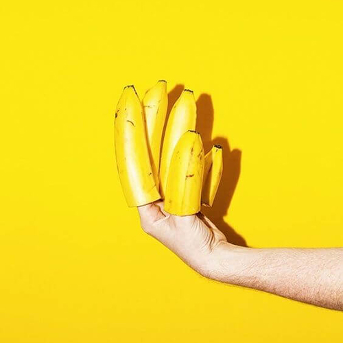 Mise en scène sur fond jaune d'une main dont les doigts sont représentés par des bouts de bananes jaunes