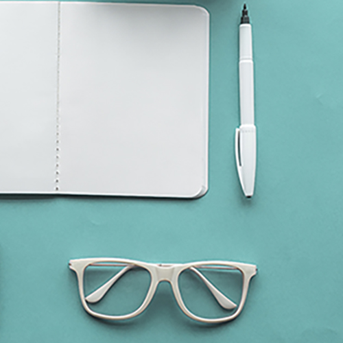 Une paire de lunettes blanches, un crayon blanc et un bloc note blanc représentés sur un fond vert